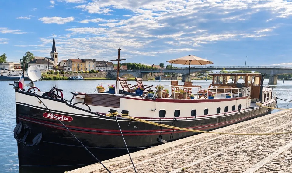 Maria in full profile beside a French town, with her bow, name and life on deck visible