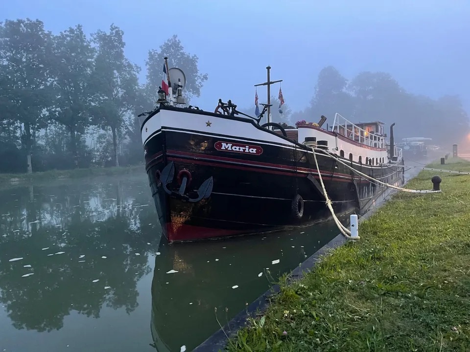 Maria moored on still water in the early morning fog, her bow and name clearly visible